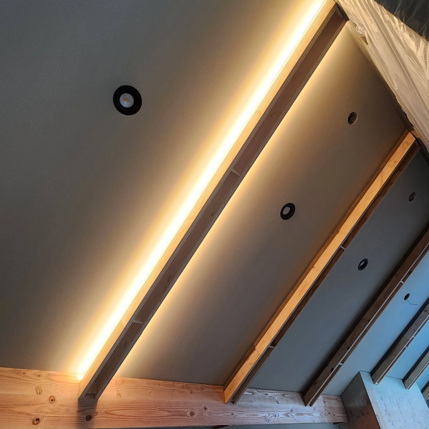 A coffered ceiling under construction in Mission with concealed LED strip lighting and recessed pot lights installed between exposed joists.