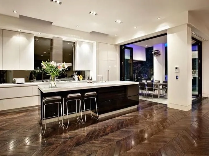 Modern kitchen with white cabinets, dark island and three bar stools.