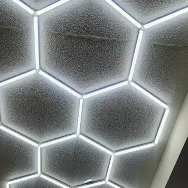 Ceiling with illuminated hexagonal LED light panels in a honeycomb pattern.