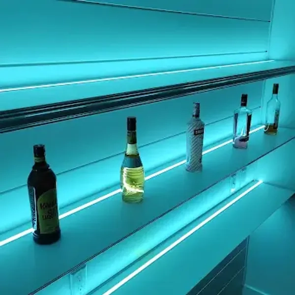 Assorted bottles on a backlit shelf with a blue neon glow.